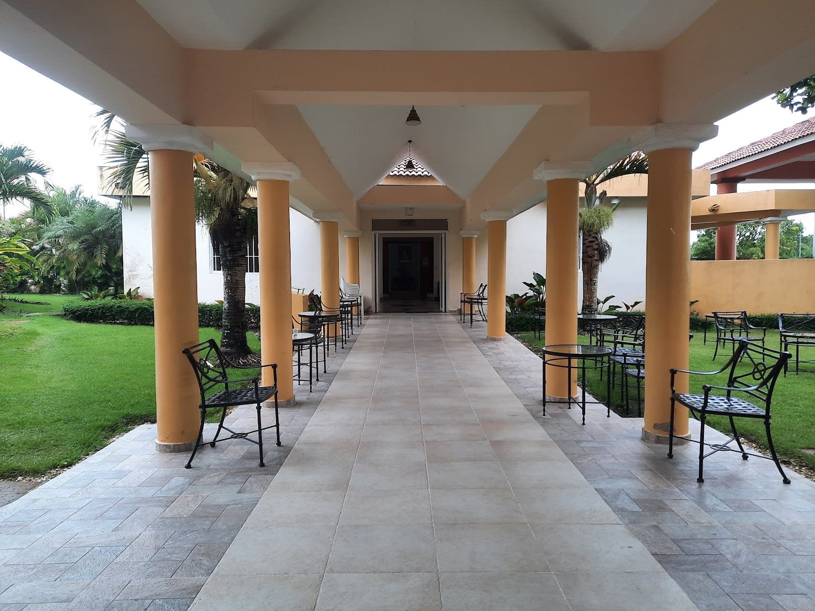 Galería cubierta del CEFIJUFA con columnas, mesas y sillas, abierta al jardín